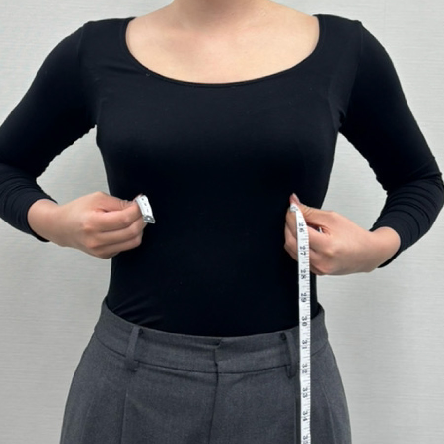 アンダーバストの測定前にメジャーを体にあてがっている女性のイメージ写真